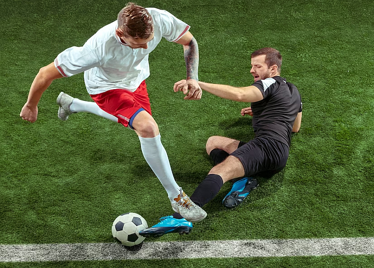 Jugador de fútbol regateando a otro jugador cerca de la línea del área rival, buscando el penalty